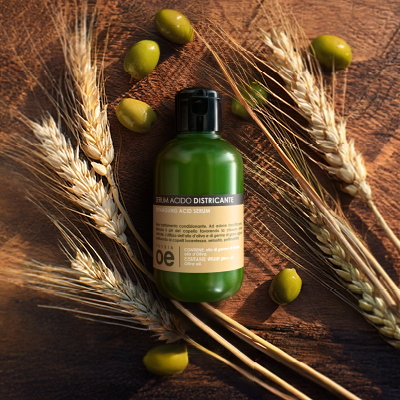 immagine del prodotto del serum acido  ambientato su sfondo marrone con grano e olive
